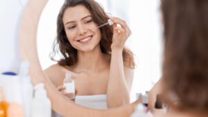 Nyári arcápolás: arcát ápoló nő a tükör előtt